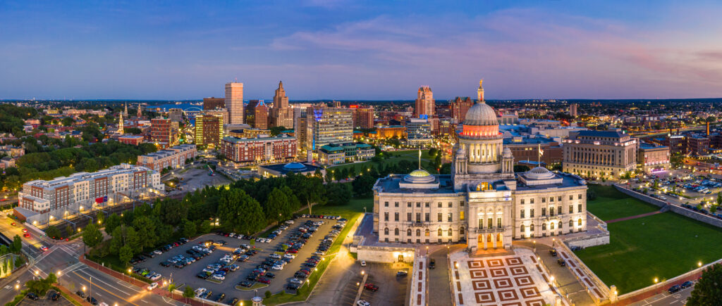 An aerial panorama of the Providence, RI, skyline and capital building at dusk.