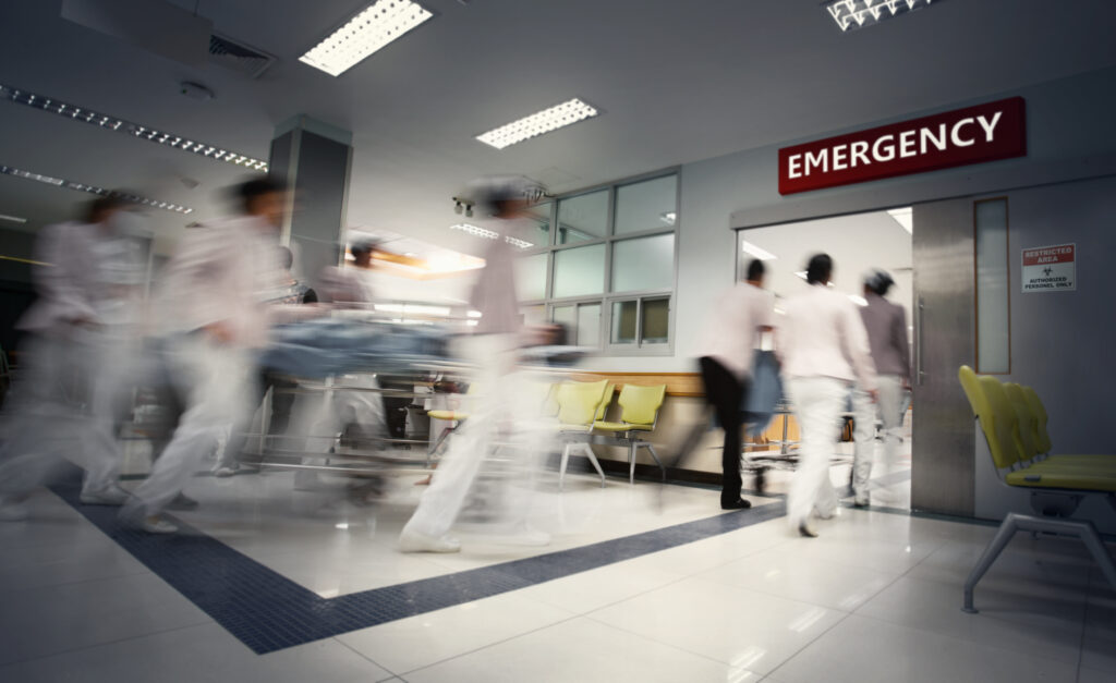 A motion blurred photograph of a patient on stretcher or gurney entering the ER.